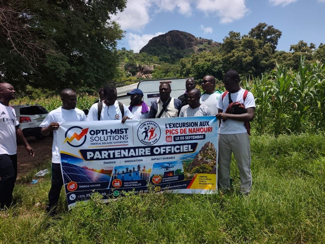 L'équipe OPTI-MIST SOLUTIONS et les membres du Club Aérobic Bassem Yam déploient la banderole de partenariat au pied des Pics de Nahouri